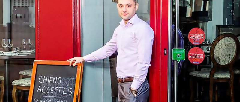 Le propriétaire du restaurant face à la pancarte
