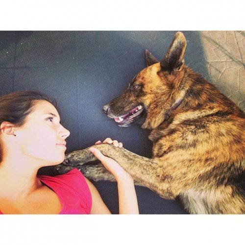 Une femme est allongée au sol avec son chien et ils se regardent